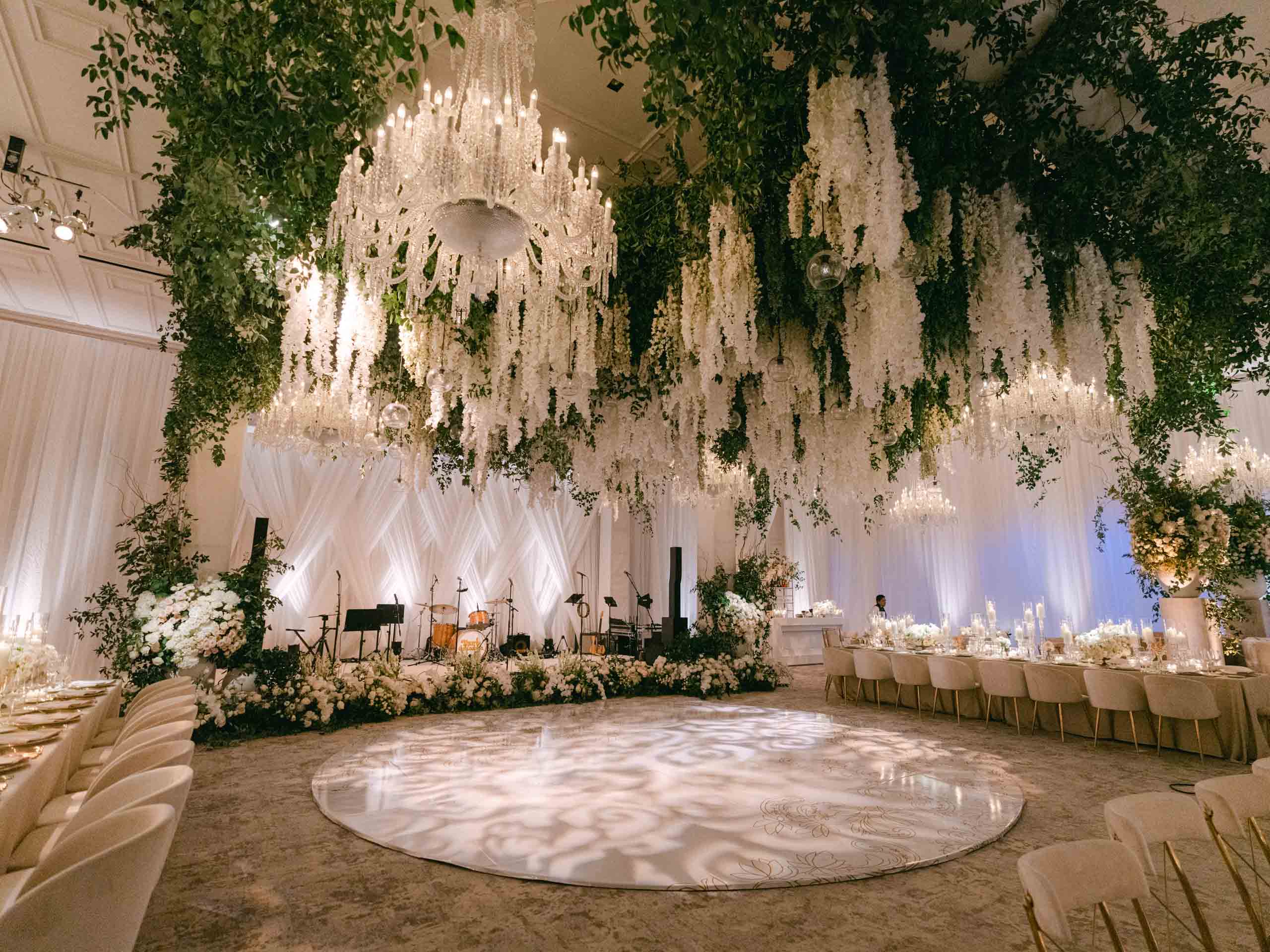 An opulent event venue space decorated with cascading floral arrangements and elegant chandeliers.