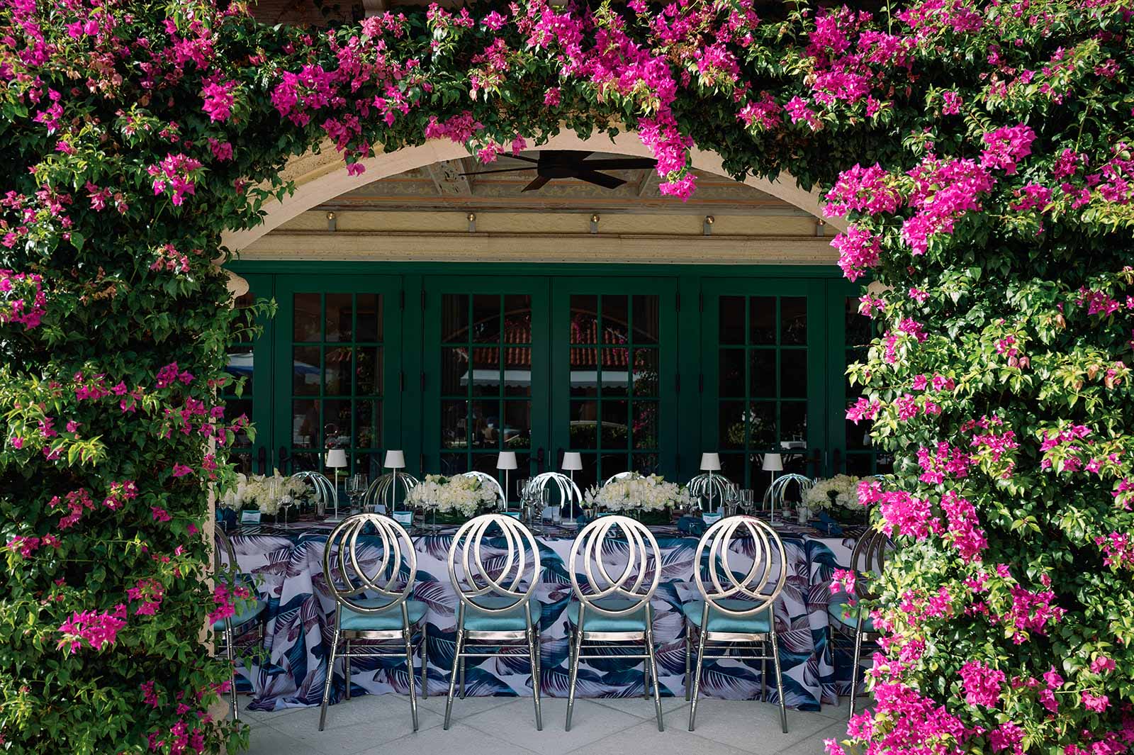 Outdoor dining area adorned with vibrant pink flowers and presented by a top-tier event planning company.